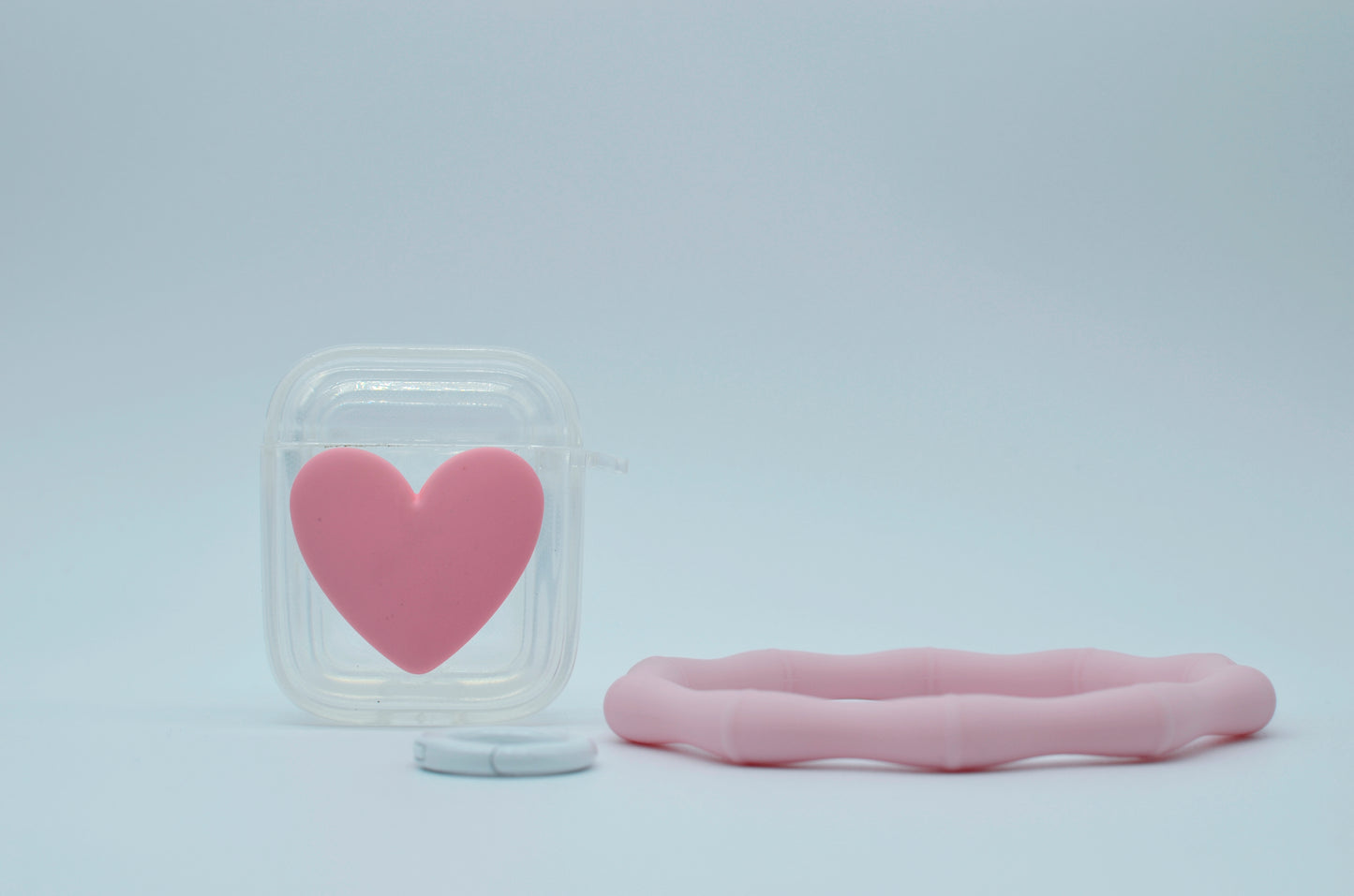 Protector para Airpods transparente con corazón rosa y pulsera de silicón